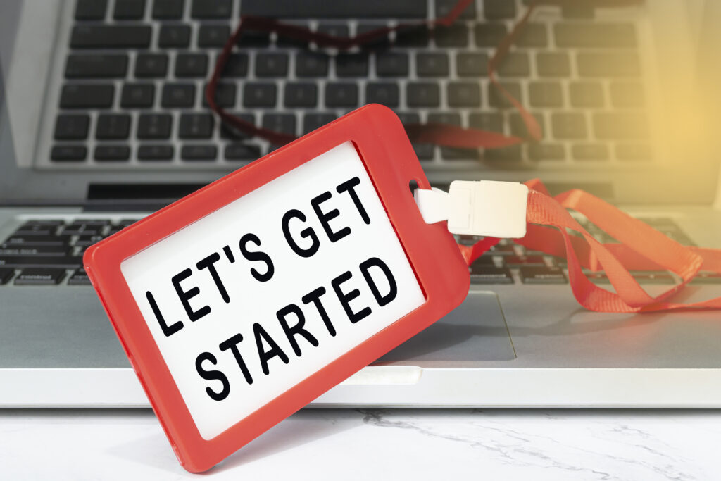 Let's get started text written on red name tag placed on a laptop or notebook.